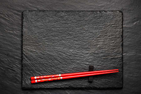Two chopsticks on black stone background with copyspace, top viewの写真素材