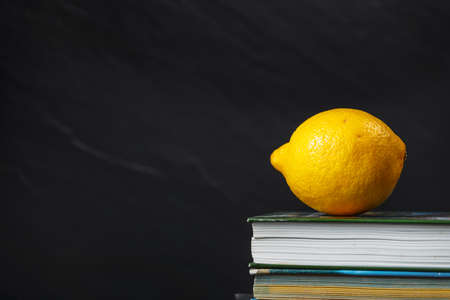 yellow lemon lying on the stack of books on black backgroundの写真素材