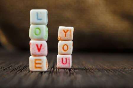 Words Love You written in ceramic blocks on brown wooden backgroundの写真素材