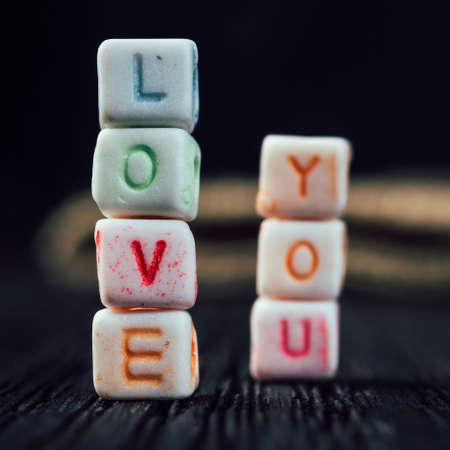 Words Love You written in ceramic blocks on brown wooden backgroundの写真素材