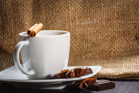 Cup of coffee with anise, chocolate and cinnamon on a wooden tableの写真素材