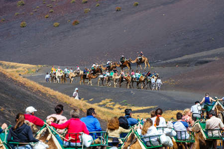 Timinfaya National Park, Lanzarote Island, Spain - March 30, 2017: Tourists riding camels in Timanfaya National Park. Camel trek is popular attraction on Lanzarote island.のeditorial素材
