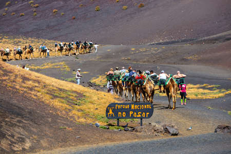 Timinfaya National Park, Lanzarote Island, Spain - March 30, 2017: Tourists riding camels in Timanfaya National Park. Camel trek is popular attraction on Lanzarote island.のeditorial素材