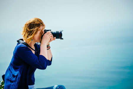 Female traveler taking a photo on the seaside