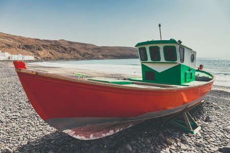 Old red fishing boat on the beachの写真素材