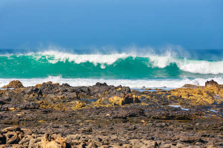 blue wave crashes down at the beach in El Cotillo village in Fuerteventura island, Spain