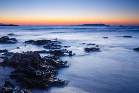 sunset over the sea and wave washing up the beach, long exposure