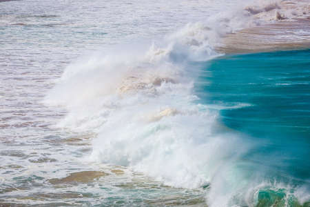 blue wave crashes down at the beach in El Cotillo village in Fuerteventura island, Spainの写真素材