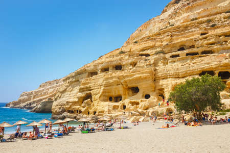 Crete Island, Greece, June 09, 2017: Panorama of Matala beach. Caves on the rocks were used as a roman cemetery and at the decade of 70's were living hippies from all over the world, Crete, Greeceのeditorial素材