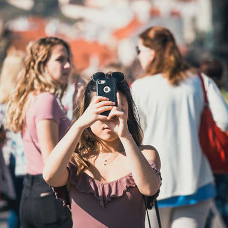 Prague, Czech Republic, September 30, 2017: Young woman is taking photos with her smartphone on Charles Bridge during beautiful autumn day, Prague, Czech Republicのeditorial素材