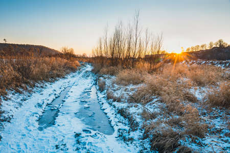 Winter landscape with snow on the ground, sunsetの写真素材