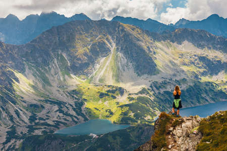 woman stands on the cliff and looks at the tops of mountainsの写真素材