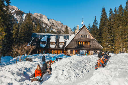 Tatra Mountains, Poland, February 14, 2015: group of tourists sit in front of a mountain hut and enjoy the sun, Koscieliska Valley, Polandのeditorial素材