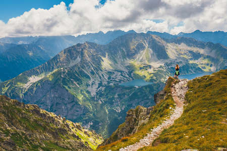 woman stands on the cliff and looks at the tops of mountainsのeditorial素材