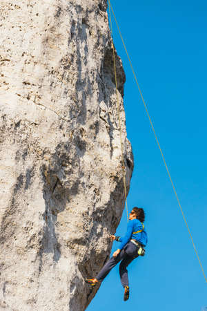 Poland, Podlesice - March 04, 2017: Side view of adult male rock climber on vertical flat wall with poor relief. Gora Zborow is a very popular destination among climbersのeditorial素材
