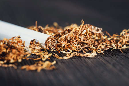 Homemade cigarettes and tobacco on the brown wooden table, close up with copy spaceの写真素材