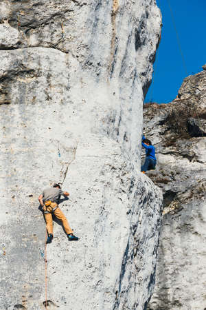 Poland, Podlesice - March 04, 2017: Side view of adult male rock climber on vertical flat wall with poor relief. Gora Zborow is a very popular destination among climbersのeditorial素材