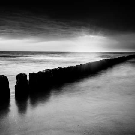 sunset over the sea with a wooden pier, black and white photo, long exposureの写真素材