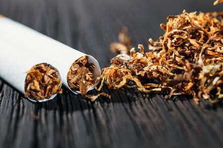 Homemade cigarettes and tobacco on the brown wooden table, close up with copy spaceの写真素材
