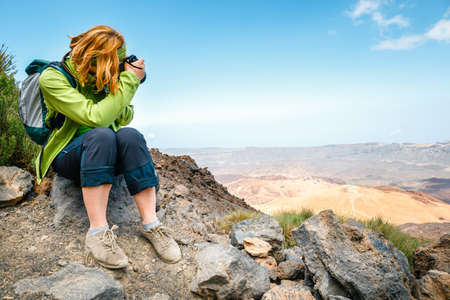 young woman admires beautiful mountain views and takes picturesのeditorial素材