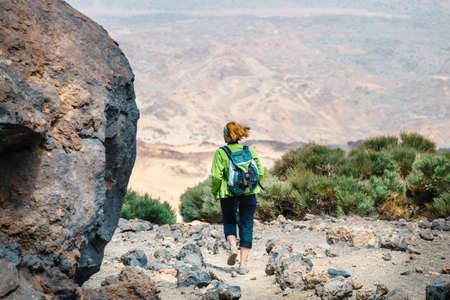 a young woman is walking in the mountains and admires beautiful viewsの写真素材
