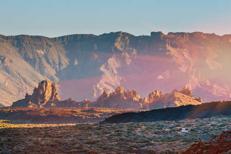 sunset over the caldera of the volcano and a bus going in the distance along the wayの写真素材