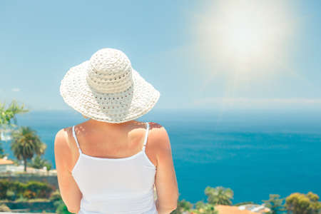 Back view of caucasian woman in white t-shirt and shawl admires beautiful viewの写真素材