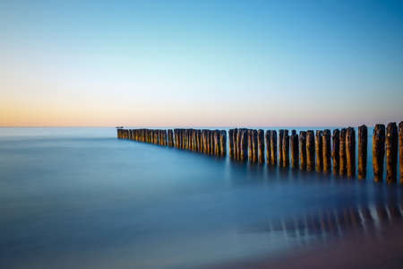 Sunset on the beach with breakwater, long time exposureの写真素材