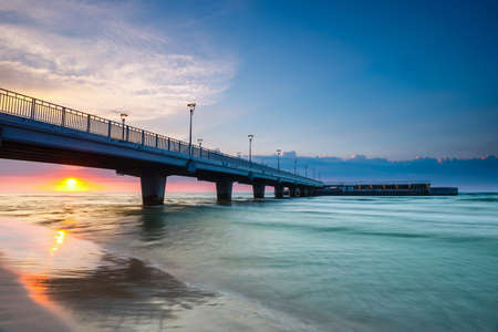 quiet beach with pier at sunset, long time exposureの写真素材