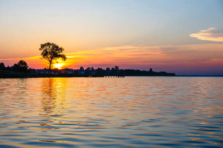 Sunrise over the lake with the tree in the backgroundの写真素材