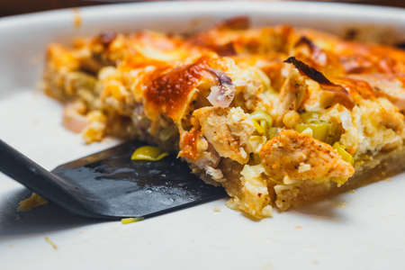 Slice of tart with meat, mushrooms, and cheese on white plateの写真素材
