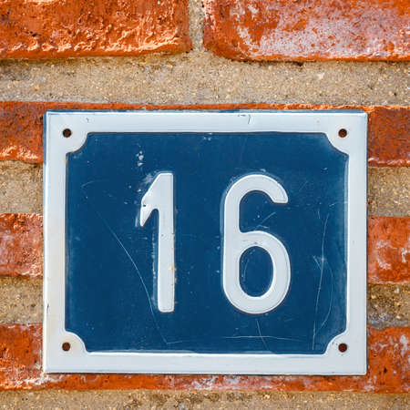 Number sixteen on a wall in a house, detail of a wall with a figure on a plateの写真素材