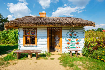 Zalipie, Poland, August 19, 2018:  Colourful house with flowers painted on walls and sundial in the village of Zalipie, Poland. It is known for a local custom of painting the cottages with decorative motifsのeditorial素材