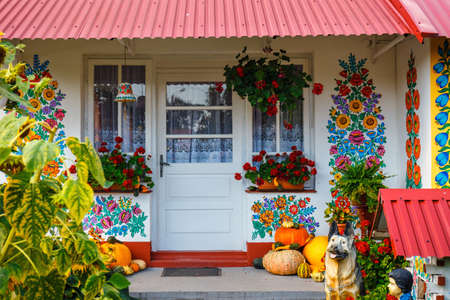 Zalipie, Poland, August 19, 2018:  Colourful house with flowers painted on walls and sundial in the village of Zalipie, Poland. It is known for a local custom of painting the cottages with decorative motifsのeditorial素材