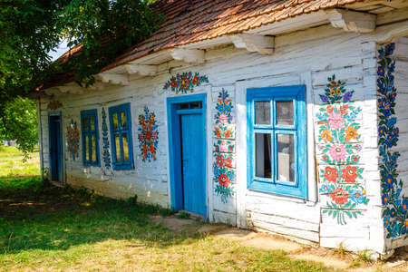 Zalipie, Poland, August 19, 2018:  Colourful house with flowers painted on walls and sundial in the village of Zalipie, Poland. It is known for a local custom of painting the cottages with decorative motifsのeditorial素材