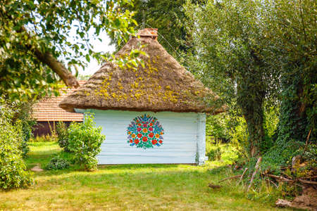 Zalipie, Poland, August 19, 2018:  Colourful house with flowers painted on walls and sundial in the village of Zalipie, Poland. It is known for a local custom of painting the cottages with decorative motifsのeditorial素材