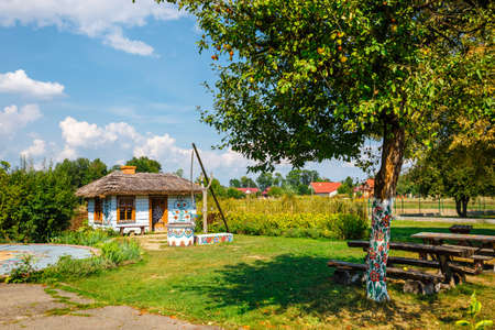 Zalipie, Poland, August 19, 2018:  Colourful house with flowers painted on walls and sundial in the village of Zalipie, Poland. It is known for a local custom of painting the cottages with decorative motifsのeditorial素材