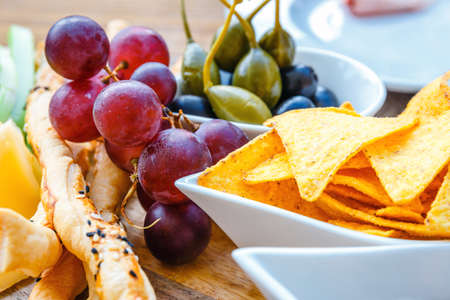 A plate of delicious tortilla nachos with grapes, pretzels and oliveの写真素材
