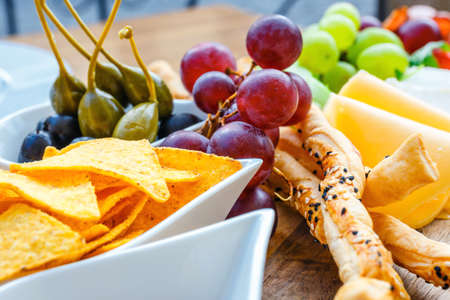 A plate of delicious tortilla nachos with grapes, pretzels and oliveの写真素材