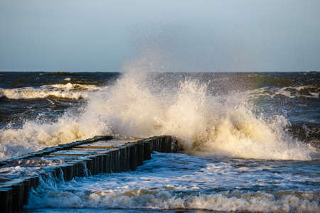 Autumn sea storm with splash from big waves over pier from the baltic coastの写真素材