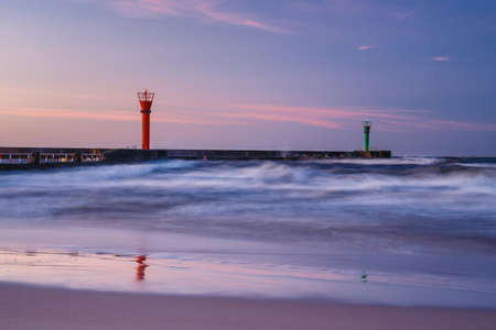 beautiful sunset with lighthouse and blue clouds over the seaの写真素材