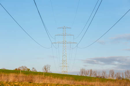 Steel high voltage poles and electric wire with blue sky and fields in rural areas.の写真素材