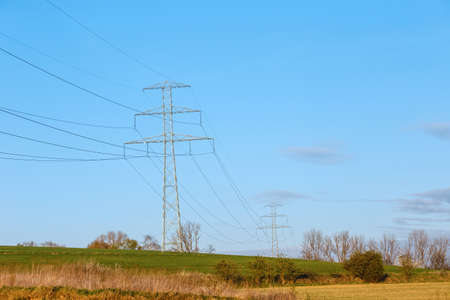 Steel high voltage poles and electric wire with blue sky and fields in rural areas.の写真素材