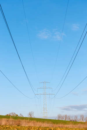 Steel high voltage poles and electric wire with blue sky and fields in rural areas.の写真素材