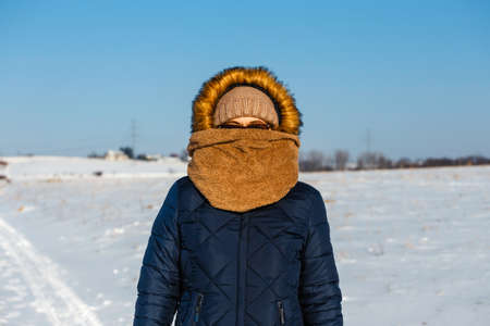 Portrait of a woman hidden behind her scarf. Sunny winter dayの写真素材