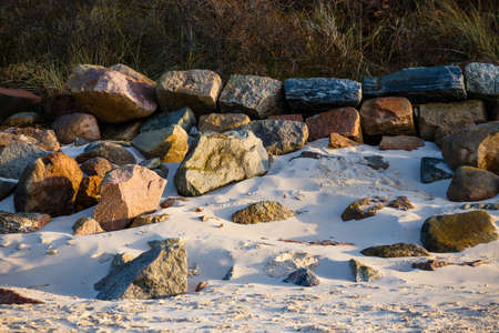 Large stones covering the yellow sand beach at sunsetの写真素材