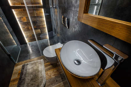 Stylish dark bathroom interior with shower. Tiles imitating wood on the floor and on the wallの写真素材