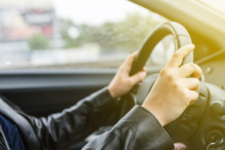 Driving a car, hands on steering wheelの写真素材