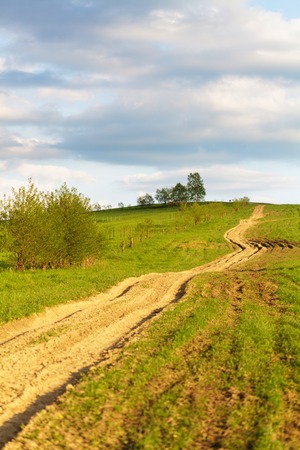 Blue cloudy sky over green hills and country roadの写真素材