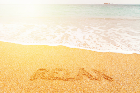 Beautiful sunny beach by the blue sea. Inscription "Relax" made on the sandの写真素材